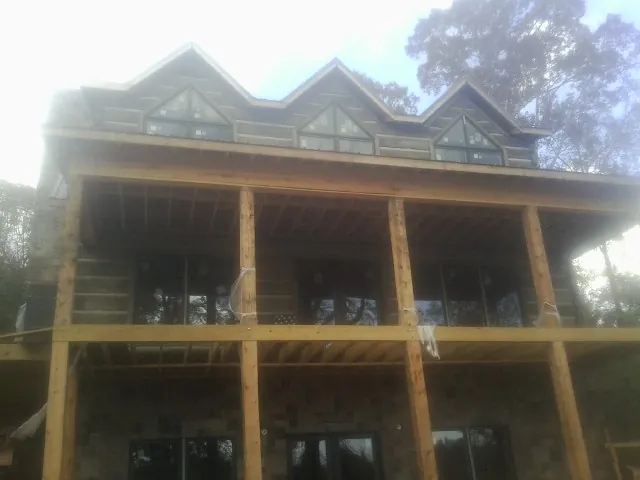 Dormers and porch framing on a large log home under construction — Roof Coating work by our crew in Cambridge