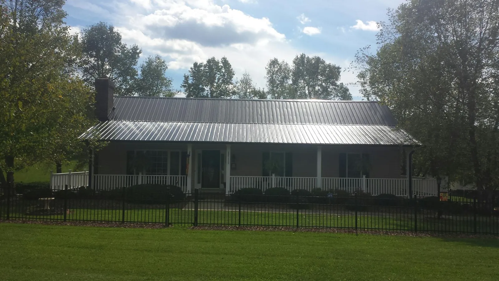 Gray metal roof on a brick ranch with a full width front porch — Gutter Guard Installation work by our crew in Cambridge